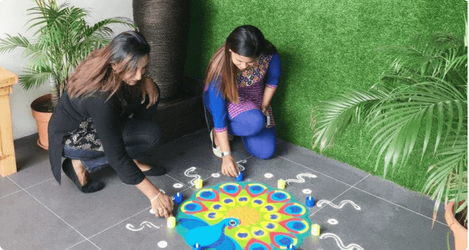 Two Malaysiakini's female staff members is painting kolam at the entrance of its building for the Deepavali celebration.
